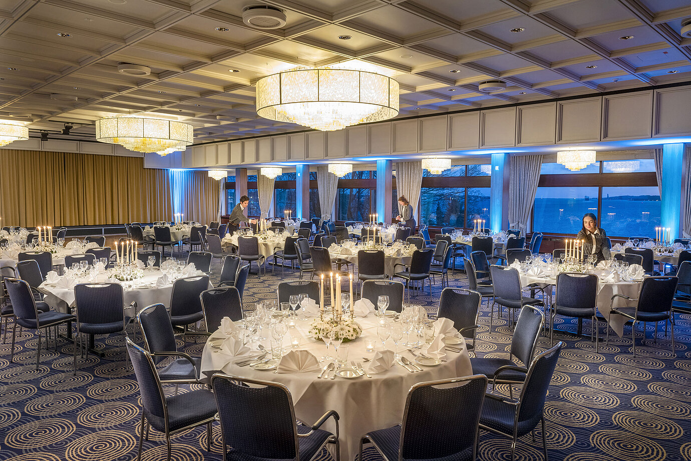 Maritim Hall in the Maritim Hotel Kiel, festively laid tables with candlelight, elegant ambience, staff preparing the event.