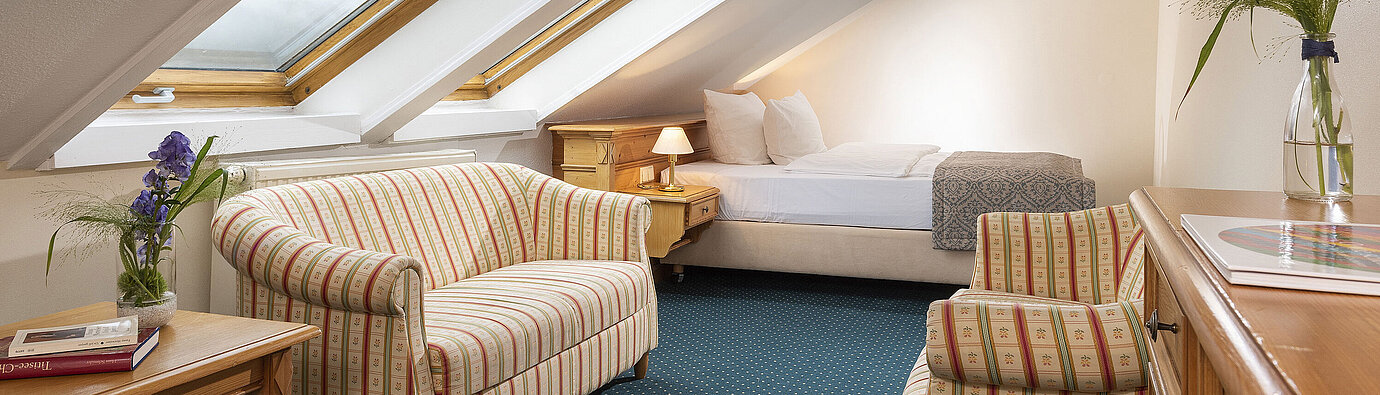 Cosy attic room with skylights, sofa and armchair at Maritim Hotel Titisee