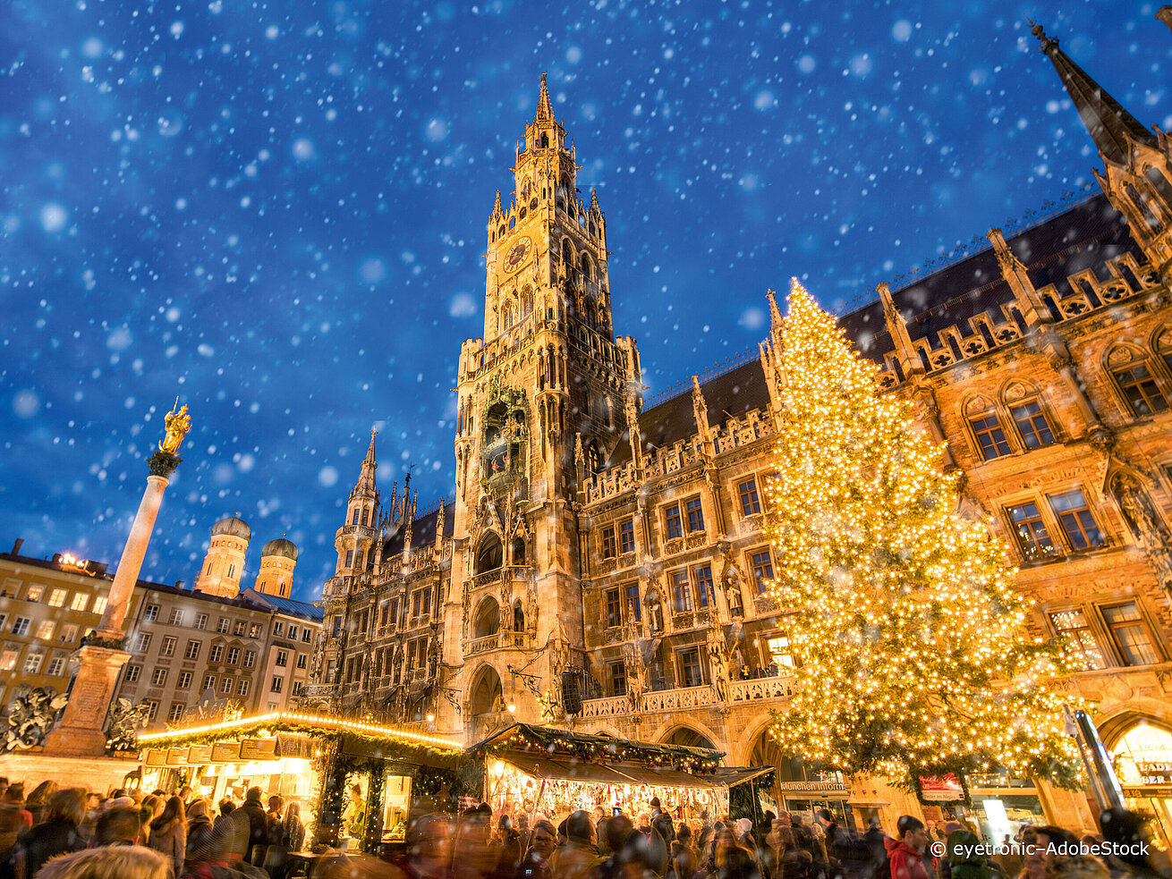 Christmas market at Marienplatz in Munich with illuminated Town Hall and large Christmas tree in the snow
