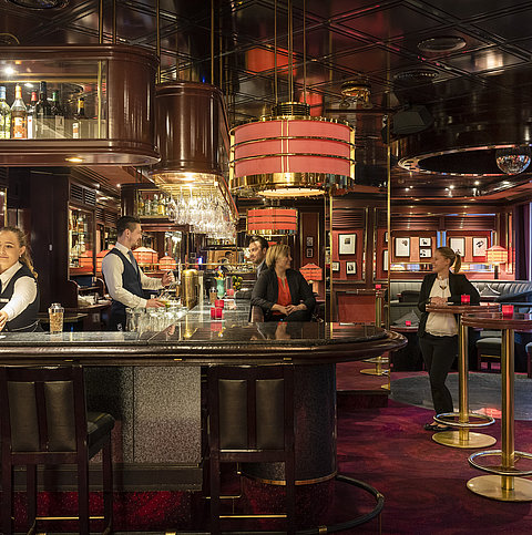 Guests enjoy drinks and a relaxed atmosphere in the stylish bar of Maritim Hotel Bremen, served by friendly staff.