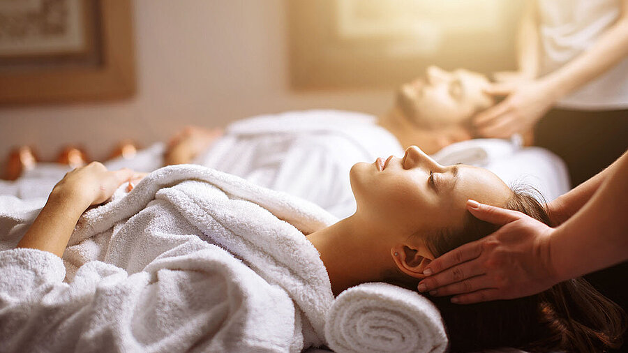 Couple enjoying relaxing head and neck massage at the spa in white bathrobes