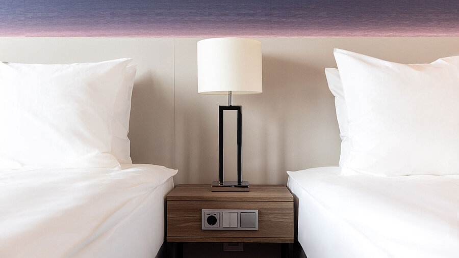 Bedside table with lamp between two beds in Maritim Hotel Amsterdam