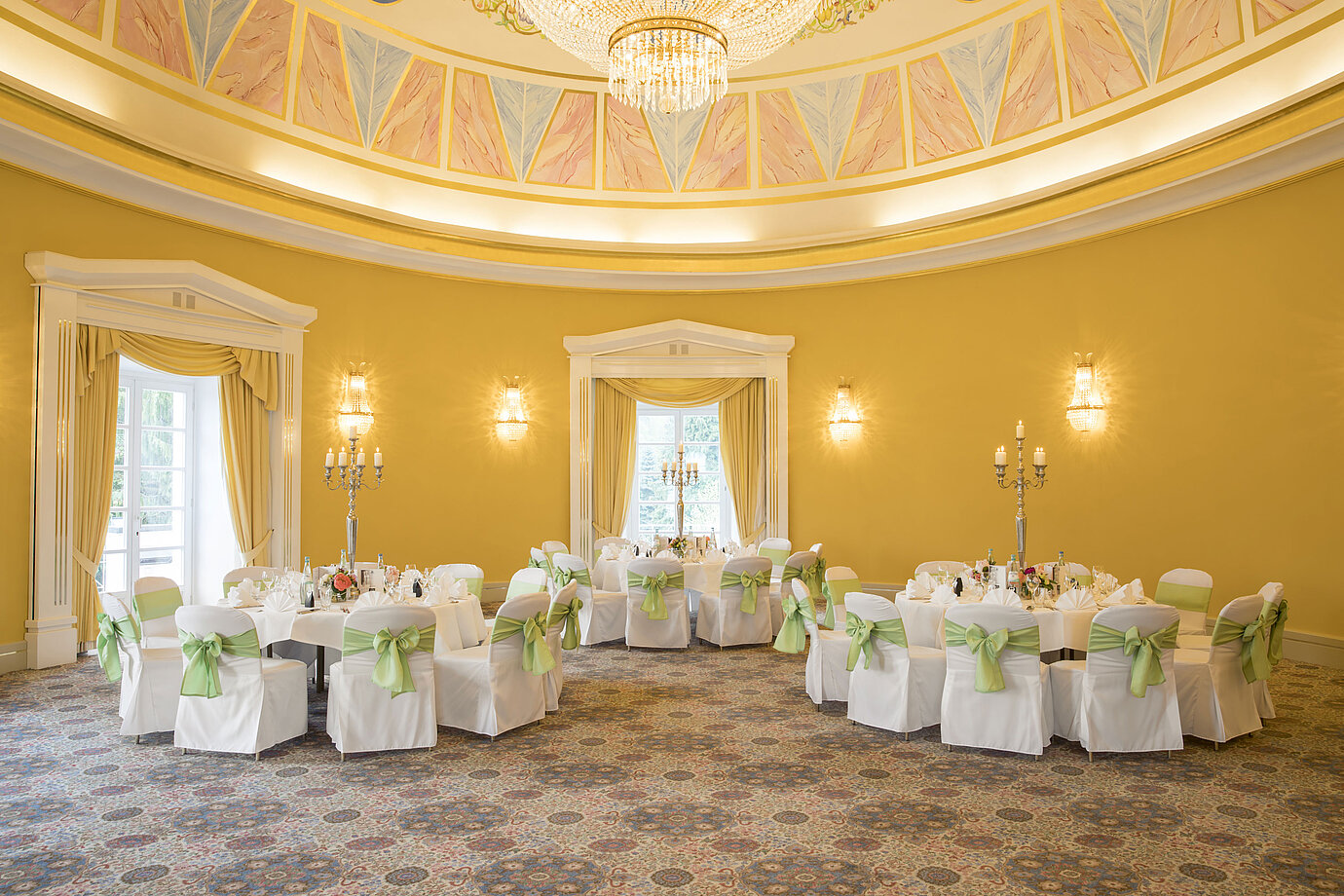 Elegant ballroom with yellow walls, round tables and candle holders at Maritim Hotel Bad Wildungen