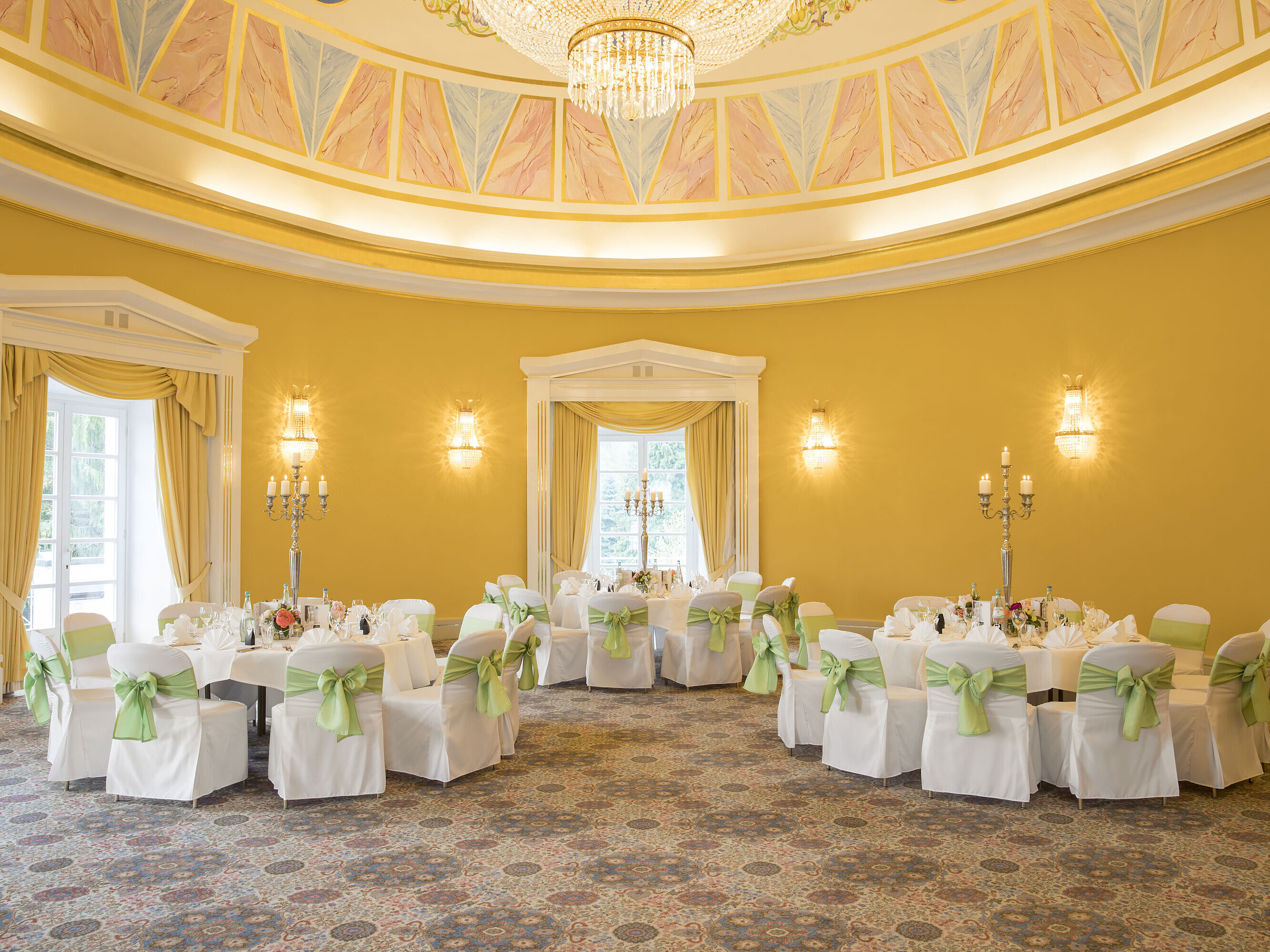 Elegant ballroom with yellow walls, round tables and candle holders at Maritim Hotel Bad Wildungen