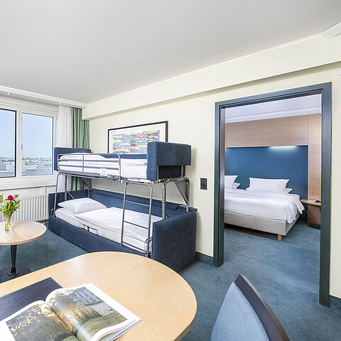 Modern family suite in the Maritim proArte Hotel Berlin with bunk bed, sitting area and separate bedroom.