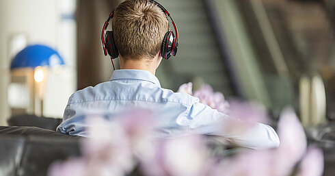 Guest relaxing with headphones in the stylish lobby of Maritim Hotel Frankfurt.