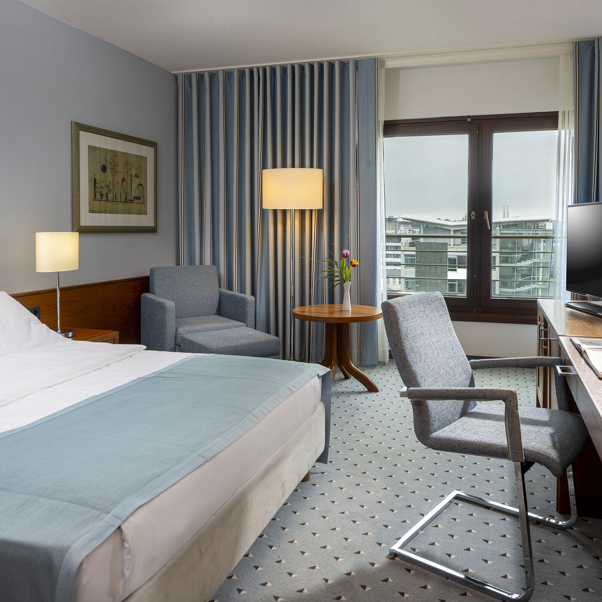 Comfort room Comfort double room at Maritim Hotel Darmstadt with cozy seating area, modern desk, and city view.
